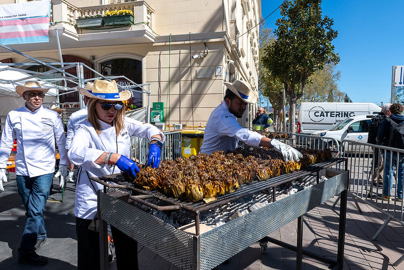 dues persones cuinant carxofes a lla brasa