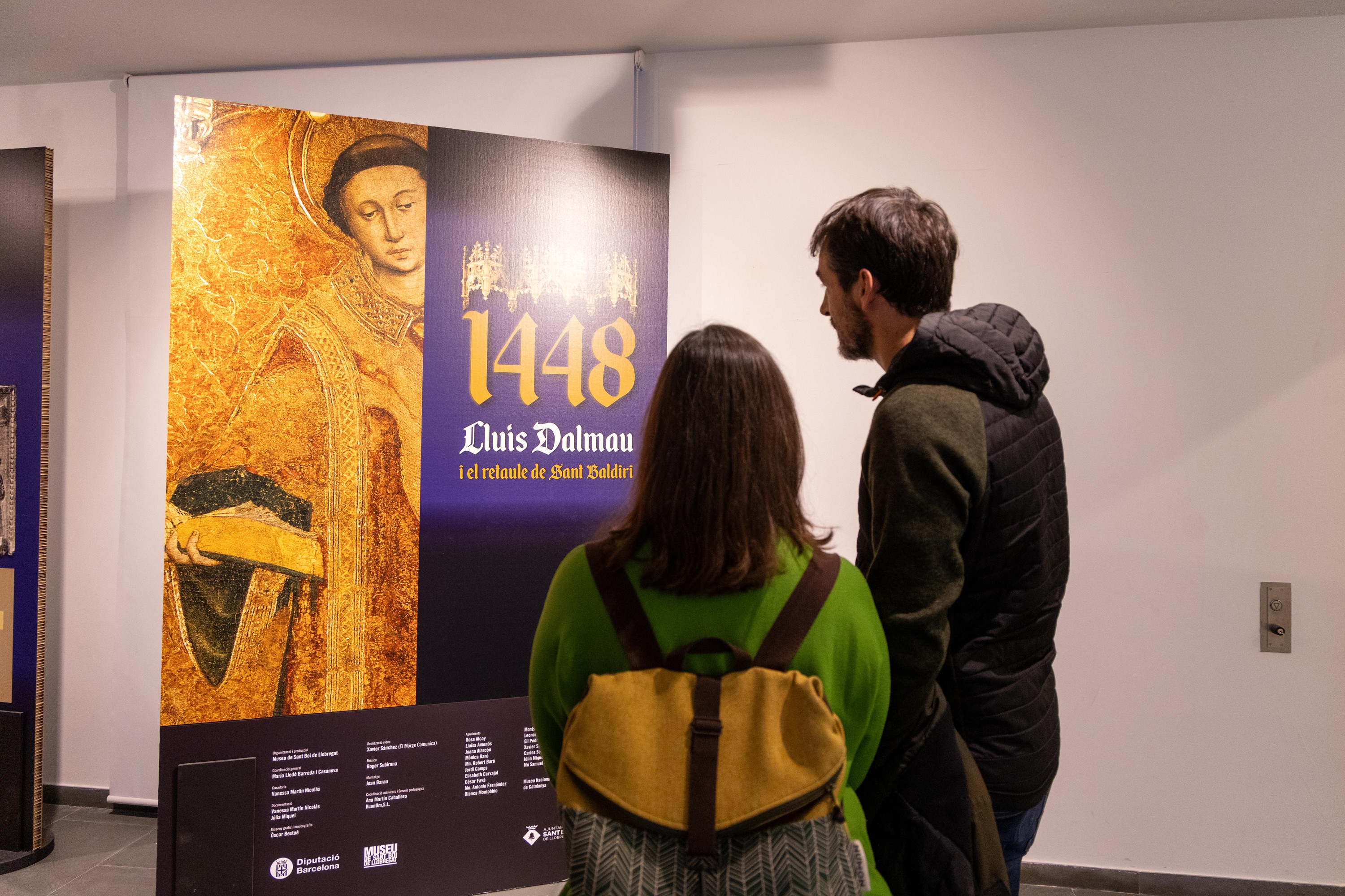 Dues persones, mirant el cartell de l'exposició a l'entrada