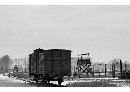 Vies de tren amb un vagó enmig d'un paisatge gris i nevat