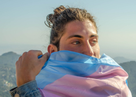 Persona tapant-se la boca amb la bandera trans