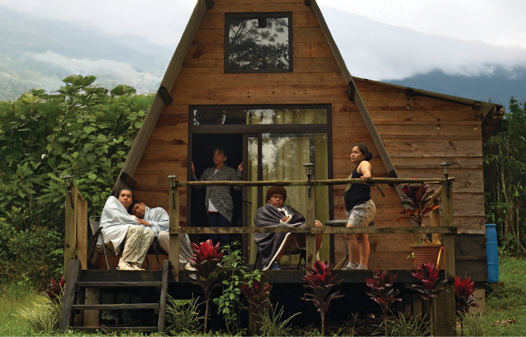 Casa de fusta triangular amb 4 persones a l'entrada