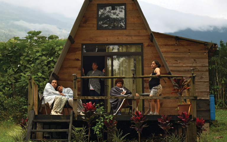 Casa de fusta triangular amb 4 persones a l'entrada