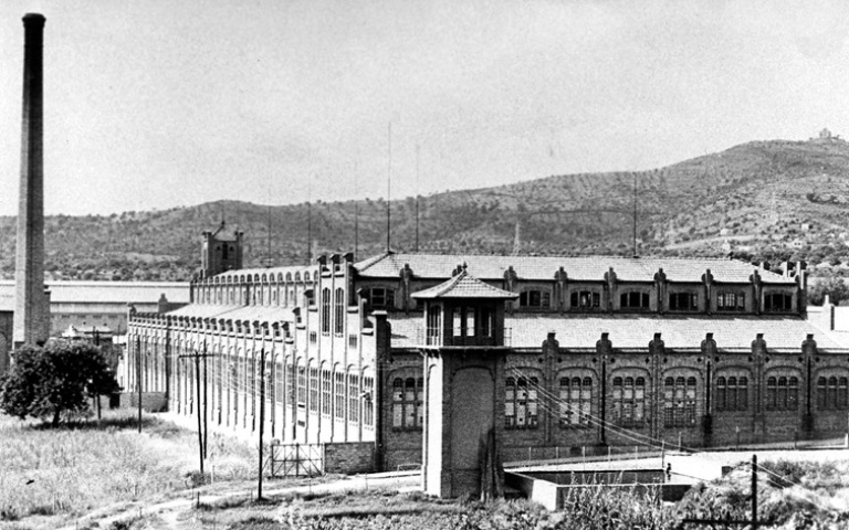 La fàbrica tèxtil de Can Massallera envoltada de garrofers