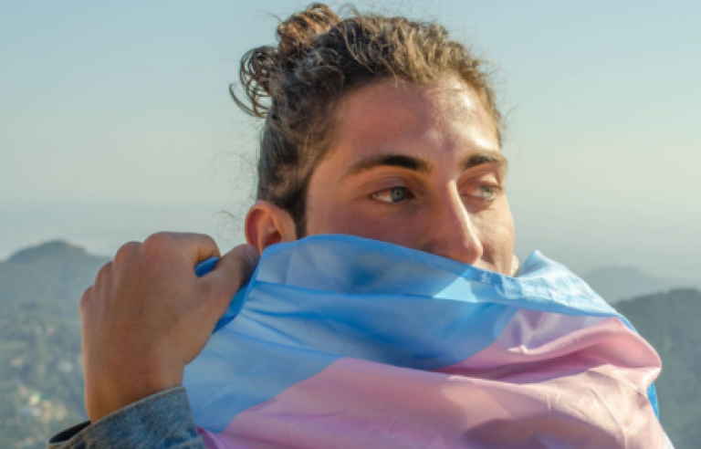 Persona tapant-se la boca amb la bandera trans